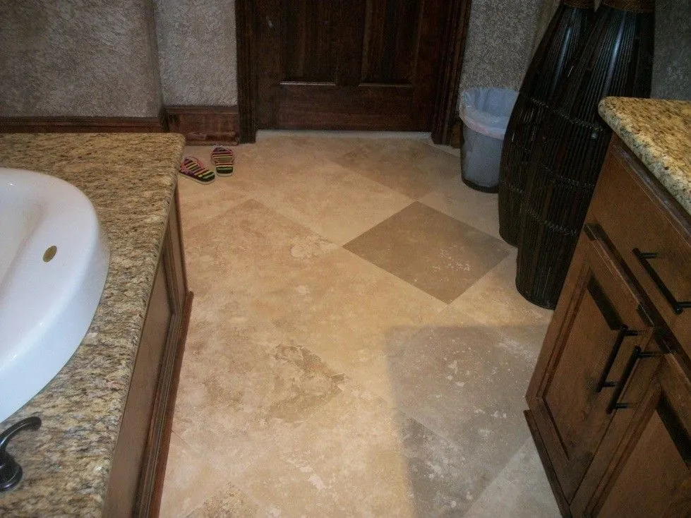 Bathroom with a tiled floor laid on the diagonal, a soaking tub with granite deck and wood vanity