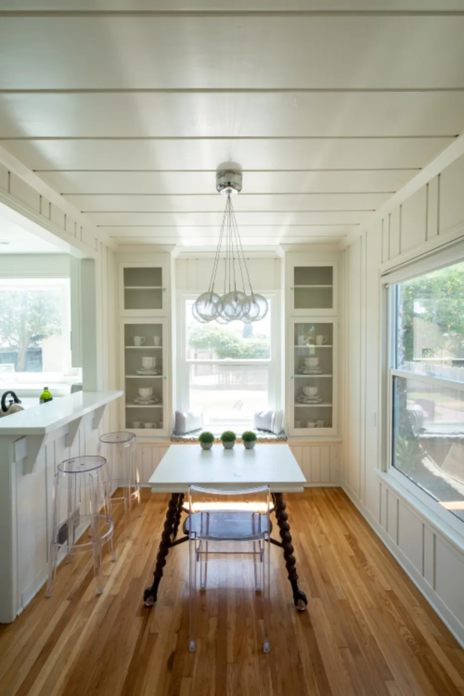 Bright dining room with a hardwood floor, white paneled walls and large windows
